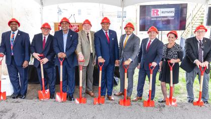 a group of men wearing red hardhats and holding shovels