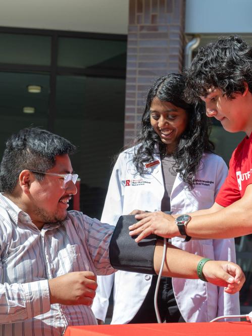 Two Rutgers Health Services Corp members giving a blood pressure check