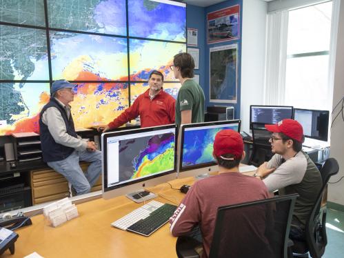 (standing l. to r.) Professor of Marine and Coastal Sciences Scott Glenn, Associate Professor of Marine and Coastal Sciences Josh Kohut, and Samuel Coakley (SEBS '18) collaborate as (sitting l. to r.) Ryan Schmidt (SEBS '22) and Research Project Assistant of the Department of Marine and Coastal Sciences Jaden Dicopoulos work in the Cool Room (Coastal Ocean Observing Leadership)