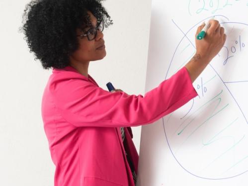 Black woman writing on whiteboard