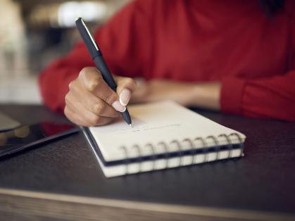 woman in red sweater writing in a notebook