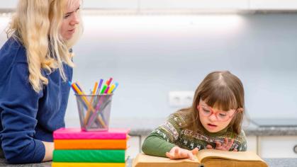 a teacher standing next to young student